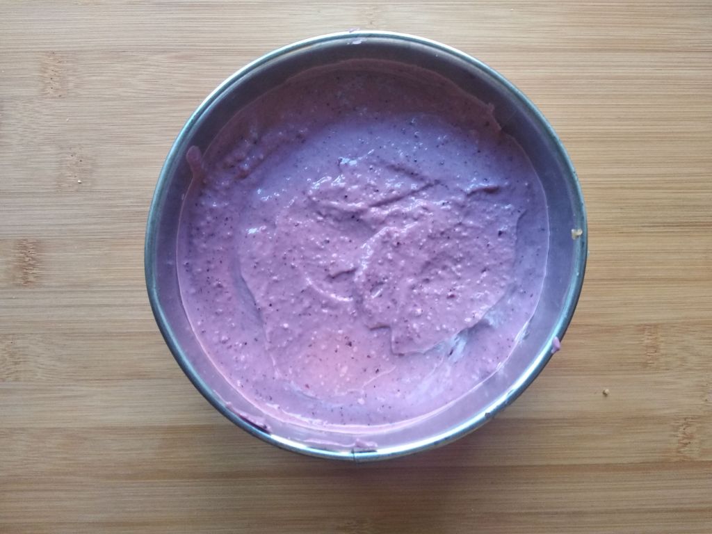 Torta crudista ai frutti di bosco nella tortiera, pronta per il frigo