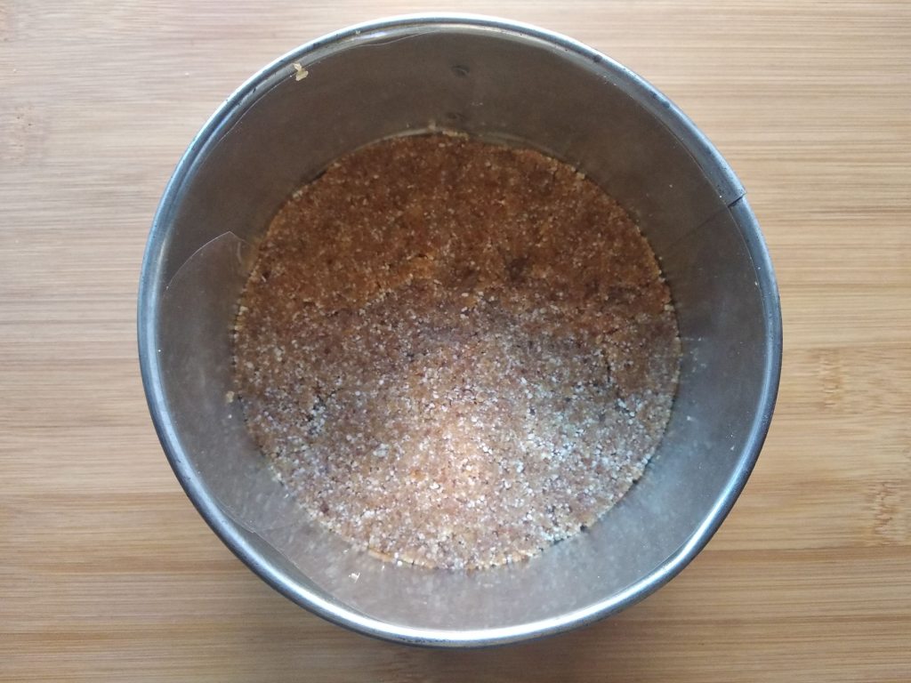 Base per la torta crudista ai frutti di bosco nella tortiera, pronta per il frigo